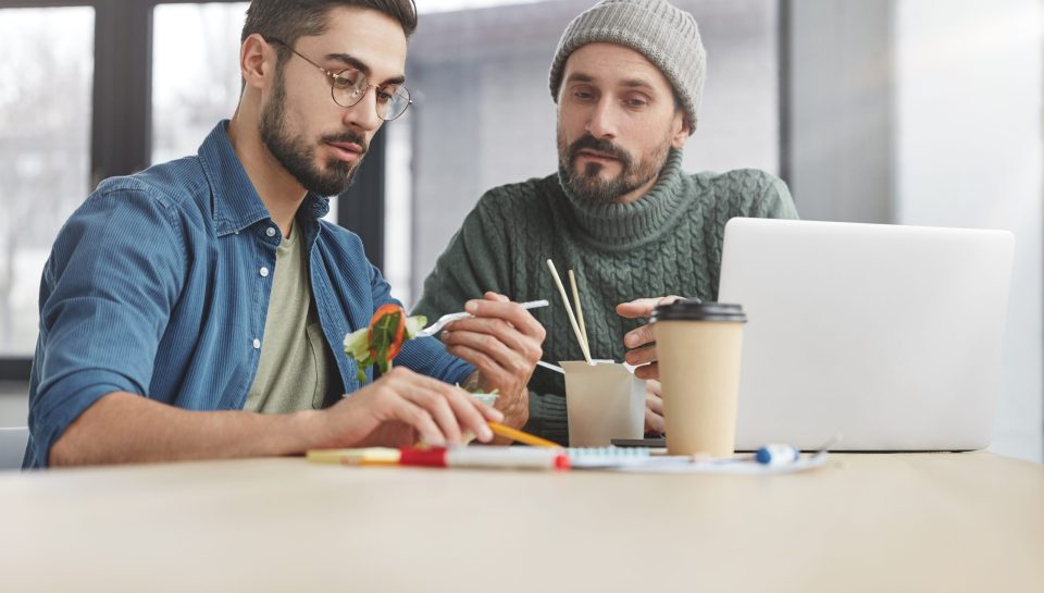 Staff memebers brainstrom together, have lunch break, finish tasks, look seriously at notes, collaborate and cooperate, have lucnchtime at modern office. People, food, business and people concept